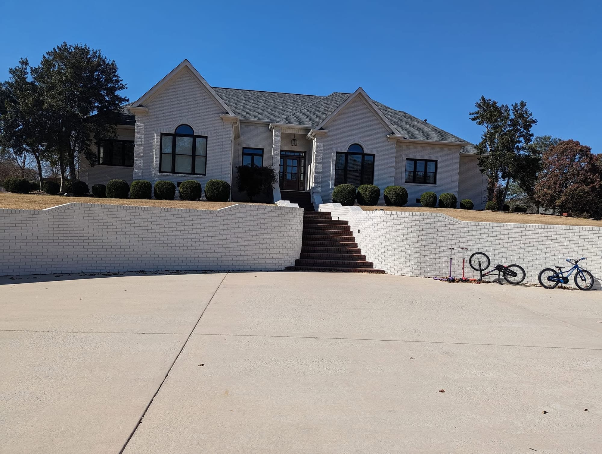 After: home exterior and retaining wall painted a light color with dark window trim